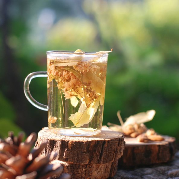 Tazza di vetro con tisana di erbe al tramonto